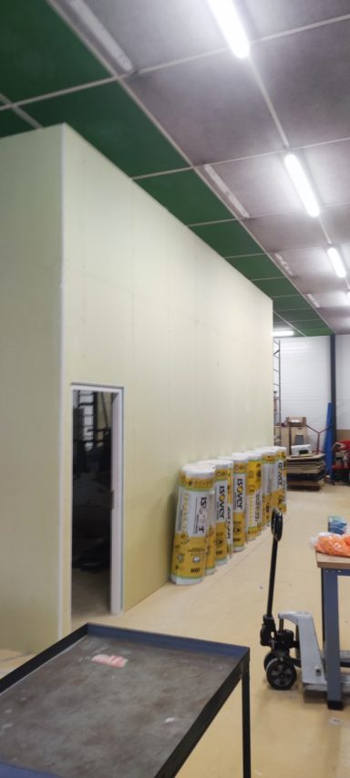 Intérieur d'un espace de travail avec murs clairs, éclairage fluorescent et équipements visibles.